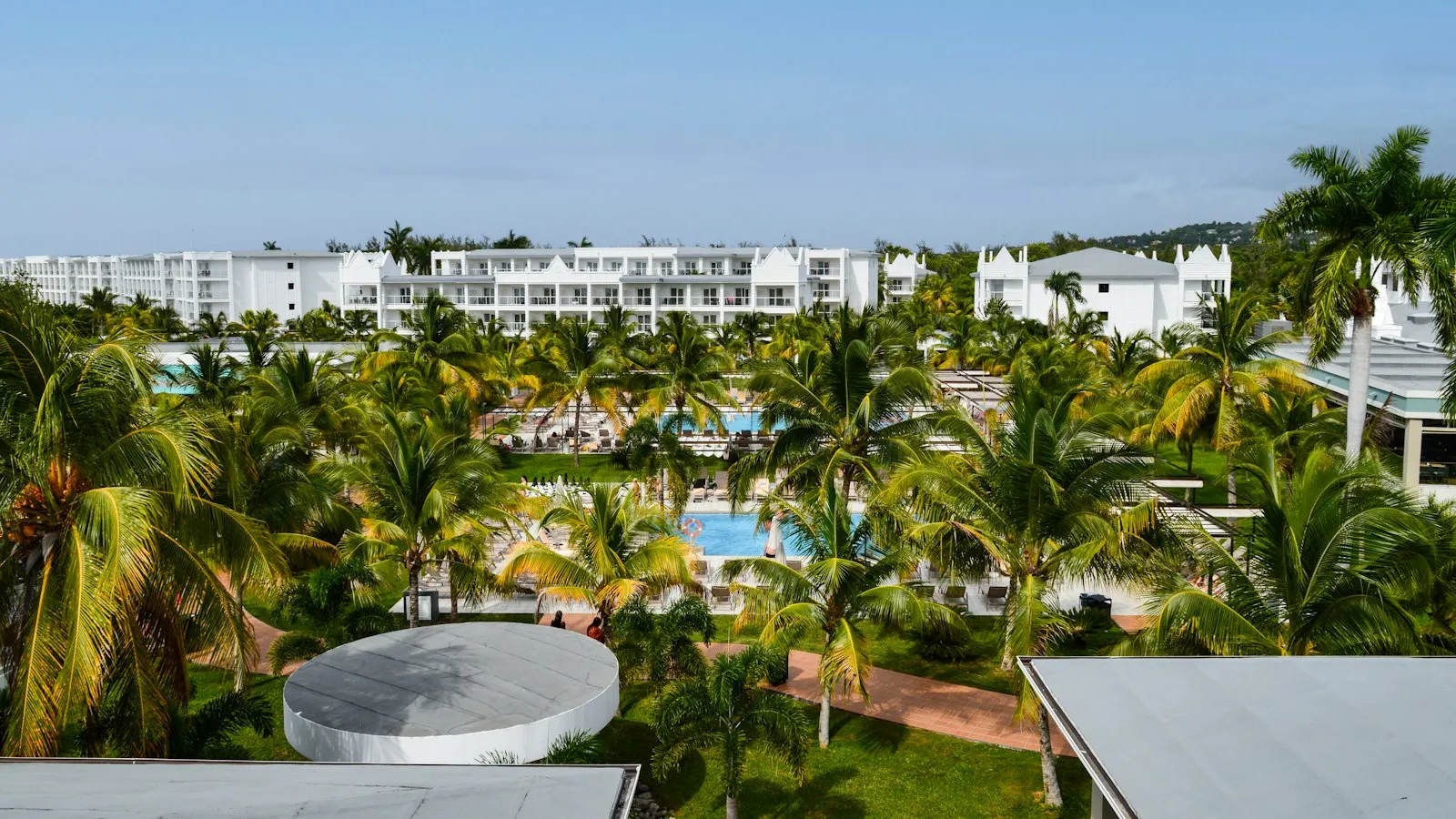 Palm-filled resort grounds with a pool and hotel buildings